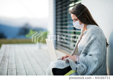 Woman working outdoors at home, Corona virus and quarantine concept. Woman working outdoors at home, Corona virus and quarantine concept. 64388731