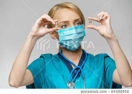 medical doctor nurse woman wearing protective mask and rubber or latex gloves - holding pills medical doctor nurse woman wearing protective mask and rubber or latex gloves - holding pills 64388958