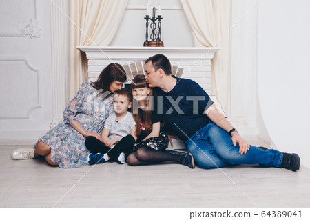 Warming and relaxing near fireplace. Mother, father and daughte, son hugging. Concept of family , motherhood, interior, home, childhood, mother's day, children's day 64389041