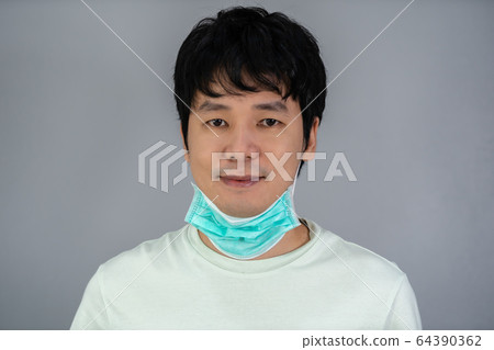 man removes medical mask (surgical mask) and man removes medical mask (surgical mask) and 64390362
