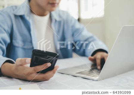Close up of man using mobile phone and laptop. Close up of man using mobile phone and laptop. 64391099