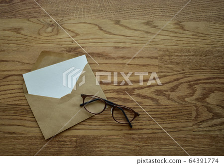 Open envelope and glasses on the desk 64391774