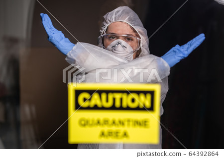 Woman in protective suit and in protective medical mask showing stop gesture. Epidemiologist show gesture no. Stop coronavirus or covid-19 and the pandemic. Stay home. Quarantine concept. Woman in protective suit and in protective medical mask showing stop gesture. Epidemiologist show gesture no. Stop coronavirus or covid-19 and the pandemic. Stay home. Quarantine concept. 64392864