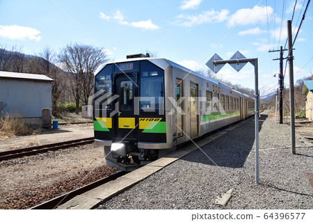 Take a picture of the scenery of an ordinary train departing and arriving at JR Shikaribetsu Station in spring 64396577