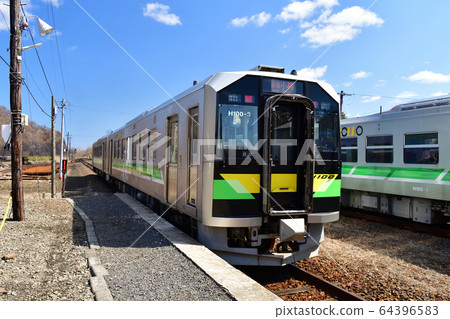 Take a picture of the scenery of an ordinary train departing and arriving at JR Shikaribetsu Station in spring 64396583