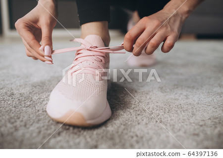 Close up of sporty sneakers on which girl tying laces 64397136