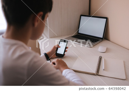 Schoolboy study at desk in his room. Boy use laptop and smartphone to writing in notebook. Books and tablet on the table. Study home during qurantine. Mock up Schoolboy study at desk in his room. Boy use laptop and smartphone to writing in notebook. Books and tablet on the table. Study home during qurantine. Mock up 64398042