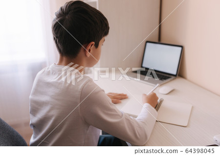 Schoolboy study at desk in his room. Boy use laptop and writing in notebook. Books and tablet on the table. Study home during qurantine Schoolboy study at desk in his room. Boy use laptop and writing in notebook. Books and tablet on the table. Study home during qurantine 64398045