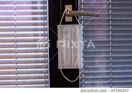 blue surgical mask hanging on door handle closed blue surgical mask hanging on door handle closed 64398207