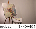 Easel with a painting and brushes nearby. Oil 64400405