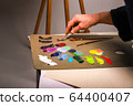 The hand of the artist works with paints. The 64400407