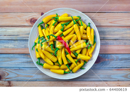 Yellow hot peppers on wooden plate 64400619