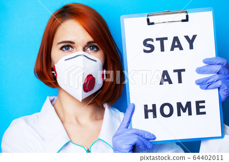 Woman holding blank with inscription stay at home calling for stop spreading covid-19. 64402011
