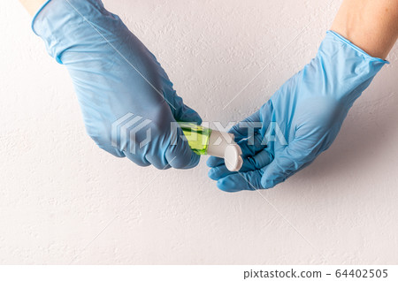 Hands in rubber surgical gloves apply antiseptic hand sanitizer on light background. Top view. Copy 64402505