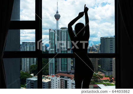 A slender girl is looking at the city through a A slender girl is looking at the city through a 64403862