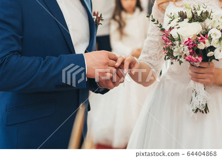 traditional wedding ceremony of exchange of gold rings between the bride and groom 64404868
