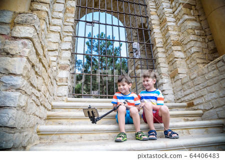 Two cute little brothers sitting on stairs in Two cute little brothers sitting on stairs in 64406483