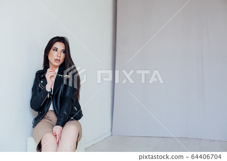 Portrait of a beautiful oriental fashionable brunette woman in a black leather jacket 64406704
