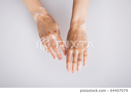 Feminime hands with soapy bubbly foam on white wall background Feminime hands with soapy bubbly foam on white wall background 64407079