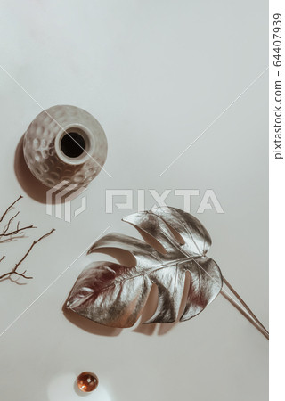 Silver leaf monstera, vase and decor on a light background. Flat lay. Abstract fashion background, minimalism. 64407939
