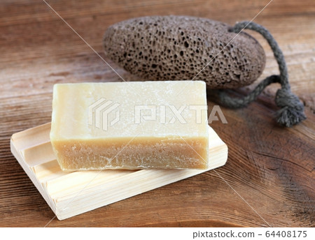 Bar of soap and on wooden pad and pumice stone in 64408175