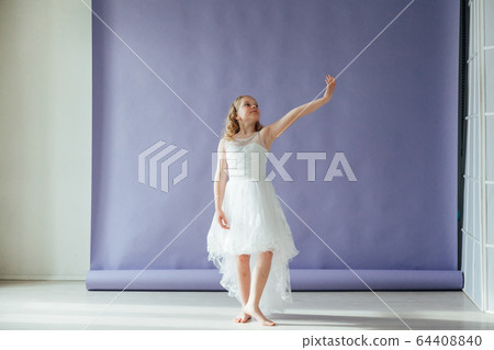 Girl in a dress dances to the music alone in the room 64408840