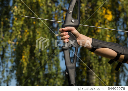 The man shoots from the bow. Close-up. Practice of archery The man shoots from the bow. Close-up. Practice of archery 64409076