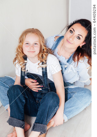 portrait of mother and daughter in denim clothes in a white room portrait of mother and daughter in denim clothes in a white room 64409294
