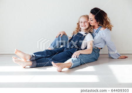 Mom and daughter in denim play in white family love room Mom and daughter in denim play in white family love room 64409303