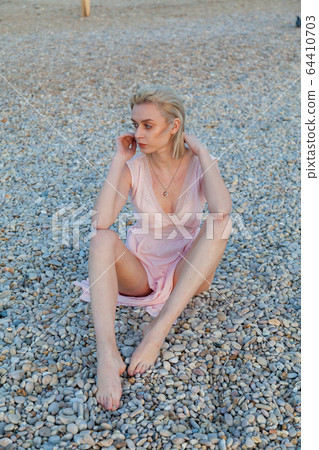 Beautiful fashionable blonde woman on the beach by the sea in lingerie Beautiful fashionable blonde woman on the beach by the sea in lingerie 64410703