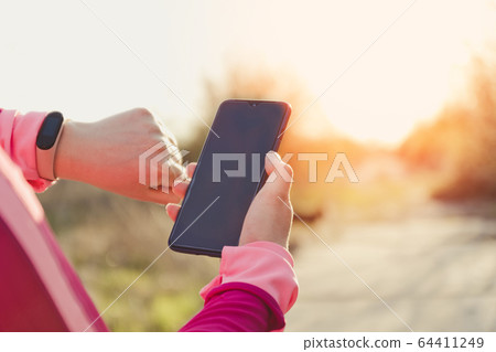 Sporty woman with fitness tracker and smartphone Sporty woman with fitness tracker and smartphone 64411249