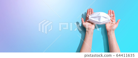 Person holding a white surgical mask overhead view 64411635