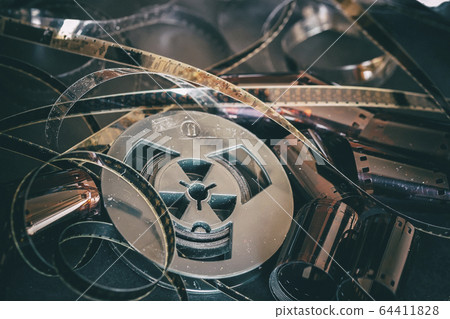 Old coil with 8 mm of film on vintage dark background of cinema strips, photographic films, retro style. Photo, movie, cinema concept Old coil with 8 mm of film on vintage dark background of cinema strips, photographic films, retro style. Photo, movie, cinema concept 64411828