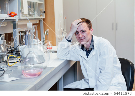 male scientist conducts chemical experiments with liquids in science lab male scientist conducts chemical experiments with liquids in science lab 64411873