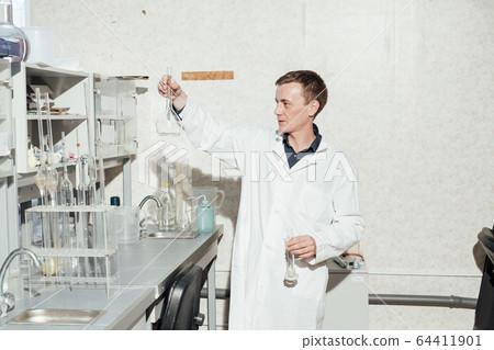 young scientist conducts chemical experiments with liquids in science laboratory young scientist conducts chemical experiments with liquids in science laboratory 64411901