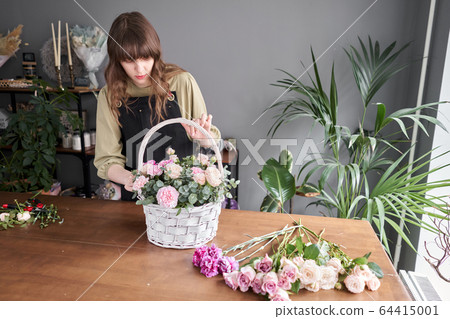 Floral shop concept . Florist woman creates flower arrangement in a wicker basket. Beautiful bouquet of mixed flowers. Handsome fresh bunch. Flowers delivery. Floral shop concept . Florist woman creates flower arrangement in a wicker basket. Beautiful bouquet of mixed flowers. Handsome fresh bunch. Flowers delivery. 64415001