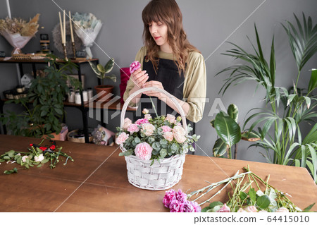 Floral shop concept . Florist woman creates flower arrangement in a wicker basket. Beautiful bouquet of mixed flowers. Handsome fresh bunch. Flowers delivery. Floral shop concept . Florist woman creates flower arrangement in a wicker basket. Beautiful bouquet of mixed flowers. Handsome fresh bunch. Flowers delivery. 64415010