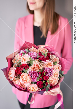 Bright berry color, Beautiful bouquet of mixed flowers in womans hands. the work of the florist at a flower shop. Delivery fresh cut flower. European floral shop. Bright berry color, Beautiful bouquet of mixed flowers in womans hands. the work of the florist at a flower shop. Delivery fresh cut flower. European floral shop. 64415022