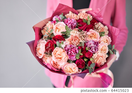 Bright berry color, Beautiful bouquet of mixed flowers in womans hands. the work of the florist at a flower shop. Delivery fresh cut flower. European floral shop. Bright berry color, Beautiful bouquet of mixed flowers in womans hands. the work of the florist at a flower shop. Delivery fresh cut flower. European floral shop. 64415023
