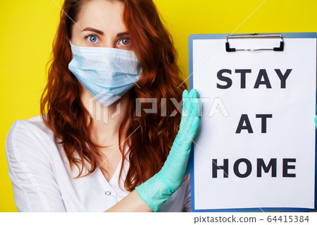 Woman holding blank with inscription stay at home calling for stop spreading covid-19. Woman holding blank with inscription stay at home calling for stop spreading covid-19. 64415384