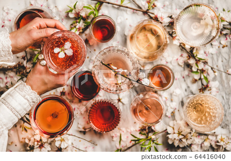 Womans hands over shades of rose wine over marble Womans hands over shades of rose wine over marble 64416040