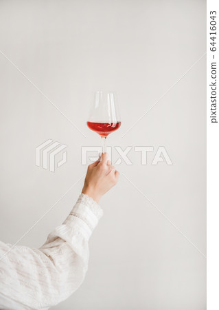 Womans hand holding glass of rose wine over white Womans hand holding glass of rose wine over white 64416043