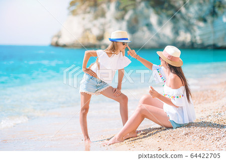 Young mother applying sun cream to daughter nose on the beach. Sun protection 64422705
