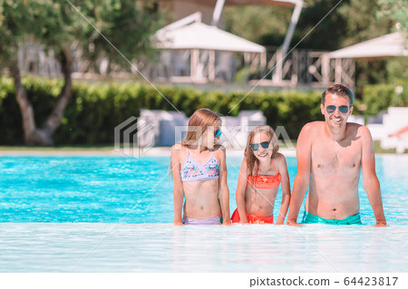Happy family of three in outdoors swimming pool 64423817
