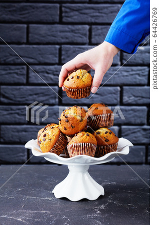 woman taking a muffin from a pile of cake woman taking a muffin from a pile of cake 64426769