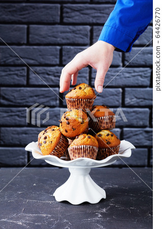 woman taking a muffin from a pile of cake 64426770