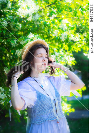 Woman in white dress near blooming apple tree Woman in white dress near blooming apple tree 64427038
