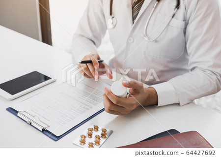 Confident doctor man holding a pill bottle and 64427692