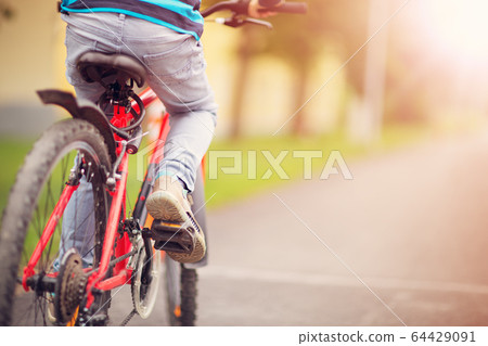 child on a bicycle at asphalt road in early morning 64429091