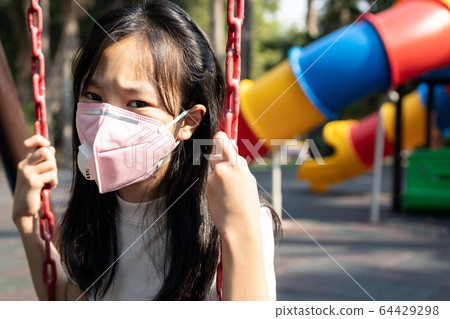 Asian child girl wearing protective mask,problems of smog,fine dust,air pollution,PM2.5,people with N95 mask to prevent danger to the respiratory system,risk of asthma,chronic bronchitis,lung cancer 64429298